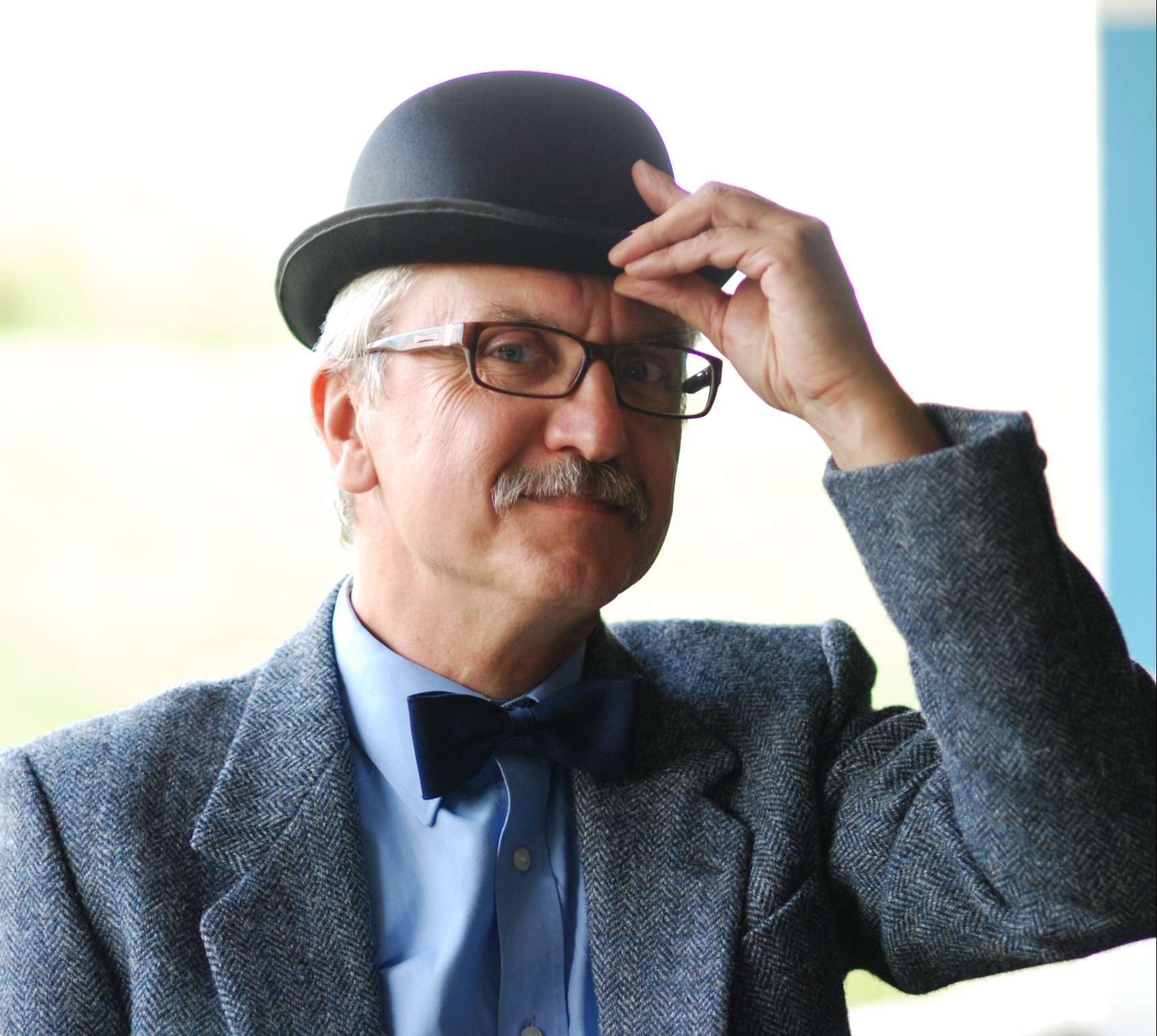 Na zdjęciu znajduje się Wojciech Widłak. Ma na sobie marynarkę, niebieską koszulę, granatową muchę. Autor ma wąsy i okulary, a na głowie kapelusz, który dotyka lewą ręką. Fot. Maciej Wróbel.